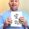 Photo of Brian Brunius holding a copy of Reiki: The Grey Book